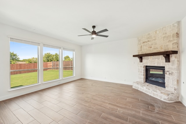 unfurnished living room featuring a stone fireplace, light hardwood / wood-style floors, and ceiling fan