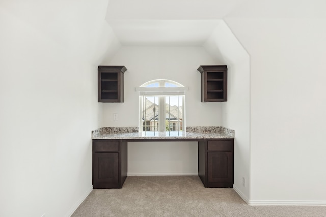 bar featuring dark brown cabinetry, lofted ceiling, and light carpet