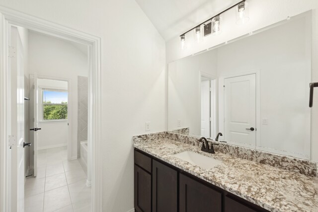 bathroom with vanity, a tub to relax in, tile patterned flooring, and lofted ceiling