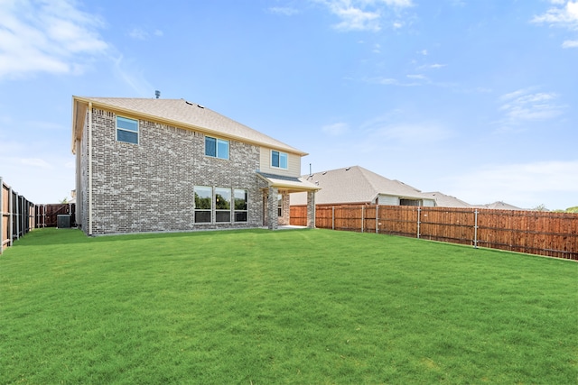 rear view of property with cooling unit and a yard