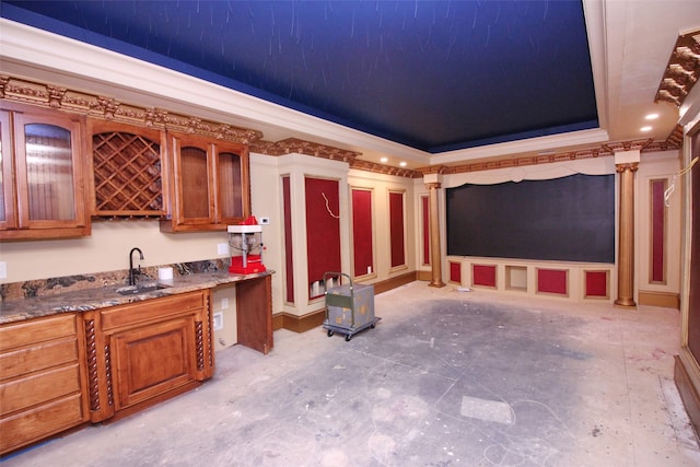 kitchen with sink, ornate columns, stone countertops, and a raised ceiling