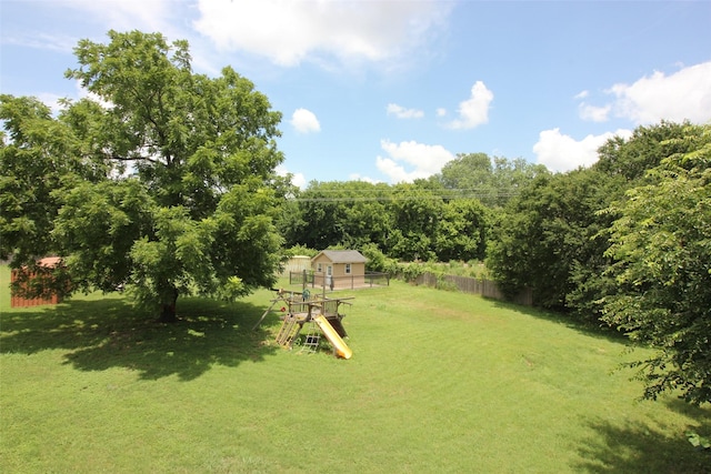 view of yard featuring an outbuilding, a playground, and fence