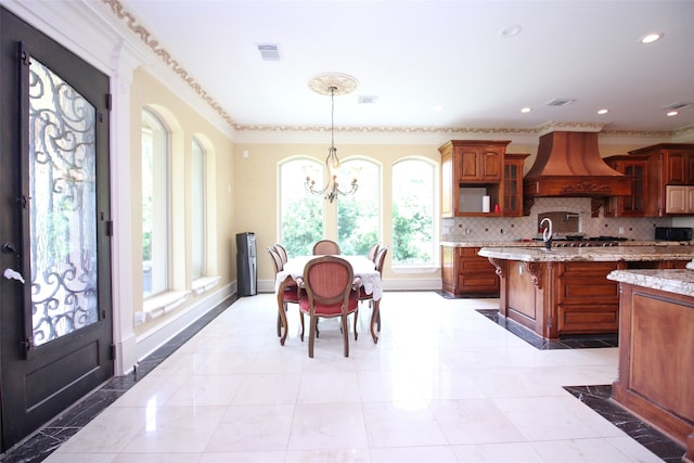 kitchen with hanging light fixtures, premium range hood, backsplash, and light tile floors