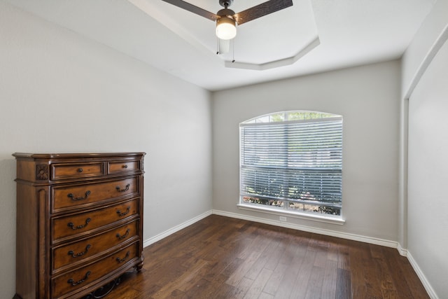 spare room featuring a raised ceiling, dark hardwood / wood-style floors, and ceiling fan