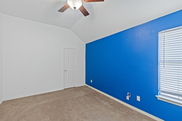 interior space featuring ceiling fan, vaulted ceiling, and light colored carpet