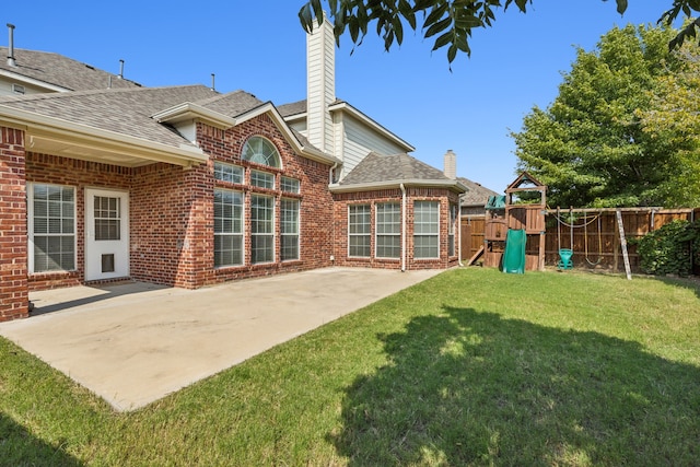 rear view of house with a playground, a patio, and a lawn