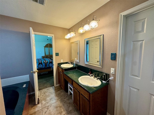 bathroom with tile patterned floors, a tub, vanity, and a textured ceiling