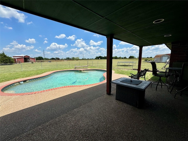 view of pool featuring a patio area, a yard, and a rural view