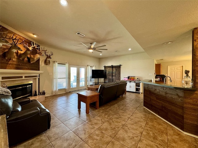 living room featuring a tile fireplace, french doors, tile patterned floors, sink, and ceiling fan