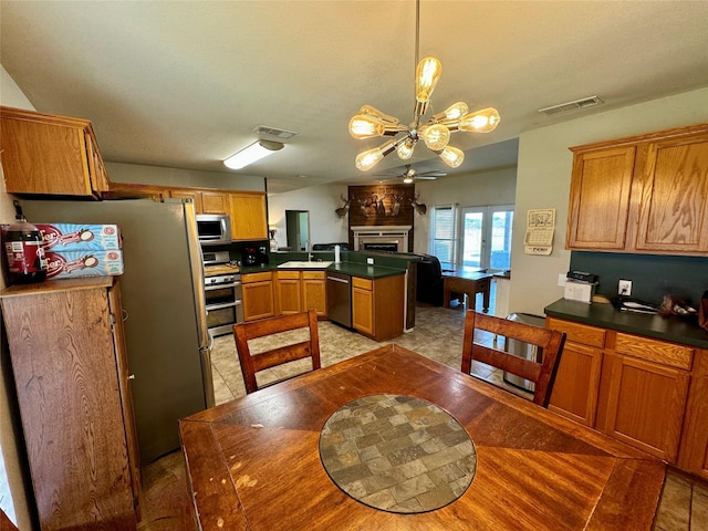 kitchen with sink, kitchen peninsula, pendant lighting, a chandelier, and appliances with stainless steel finishes