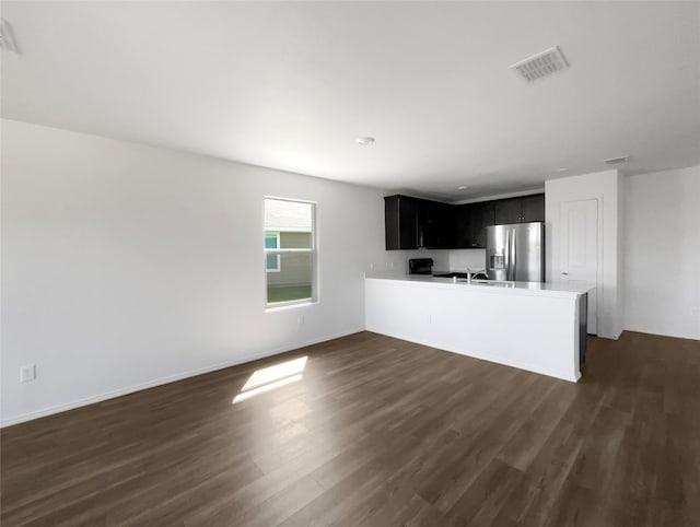 kitchen with sink, dark hardwood / wood-style floors, kitchen peninsula, and stainless steel refrigerator with ice dispenser