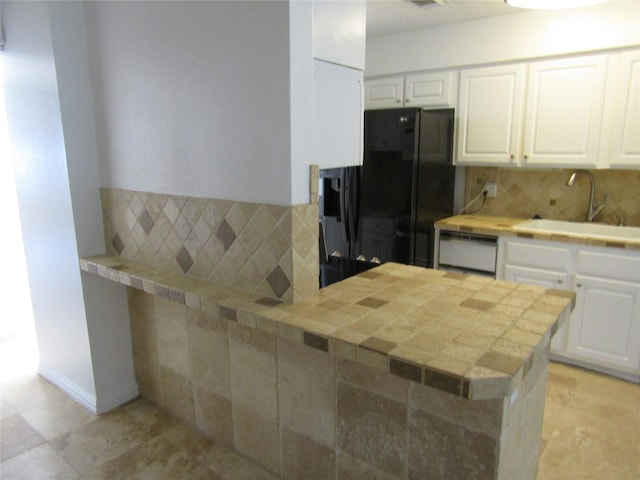 kitchen featuring white cabinets, black refrigerator, and kitchen peninsula