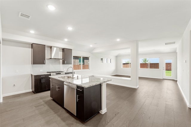 kitchen featuring light hardwood / wood-style floors, stainless steel dishwasher, a kitchen island with sink, sink, and wall chimney range hood