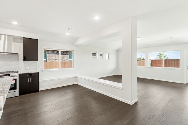 interior space with gas stove, dark wood-type flooring, decorative backsplash, dark brown cabinetry, and light stone countertops