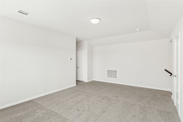 empty room featuring light colored carpet and lofted ceiling