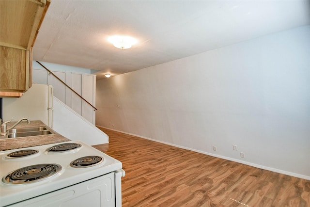 kitchen featuring white electric range, light hardwood / wood-style flooring, light brown cabinetry, and sink