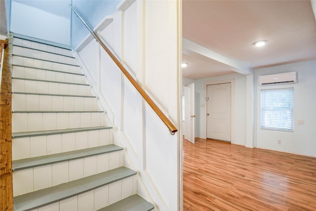 stairway featuring a wall mounted AC and hardwood / wood-style floors