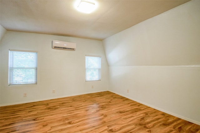 bonus room featuring light hardwood / wood-style flooring, a wall mounted AC, and lofted ceiling