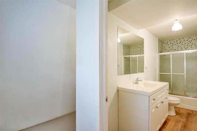 full bathroom featuring shower / bath combination with glass door, hardwood / wood-style flooring, vanity, and toilet