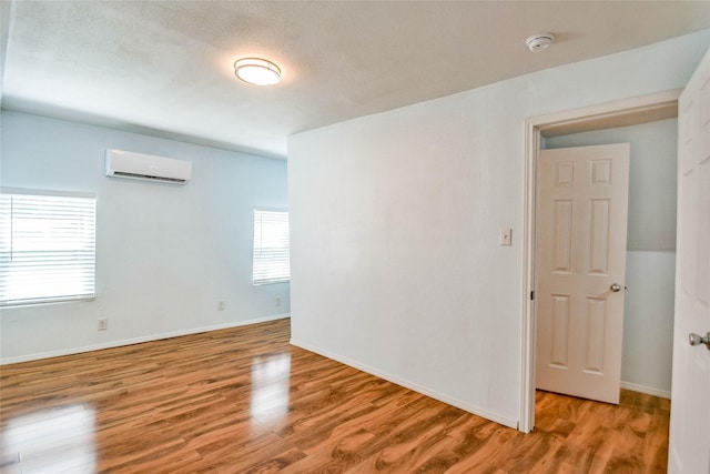 spare room featuring plenty of natural light, light hardwood / wood-style floors, and a wall unit AC