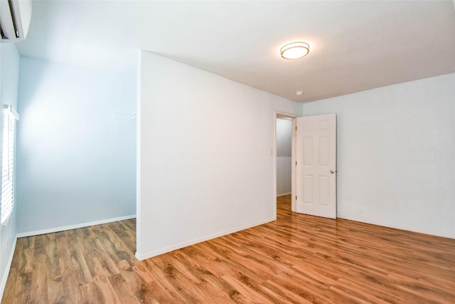 empty room with light hardwood / wood-style floors and a wall mounted air conditioner