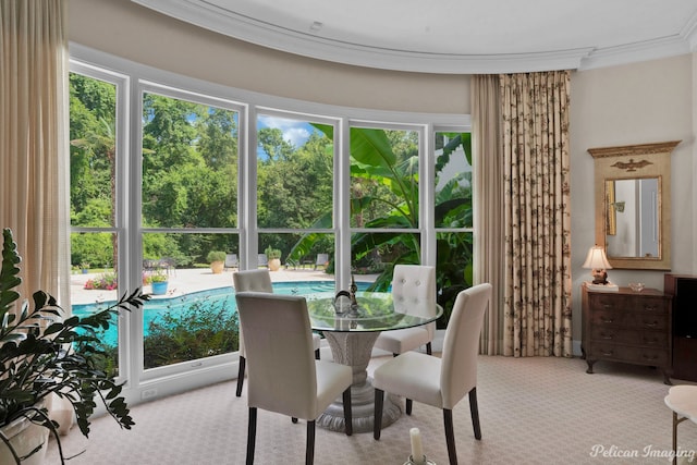 dining space with ornamental molding and light colored carpet