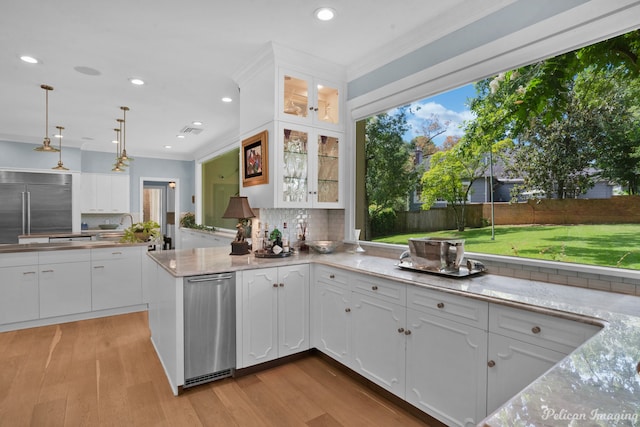 kitchen with kitchen peninsula, tasteful backsplash, light wood-type flooring, white cabinets, and appliances with stainless steel finishes