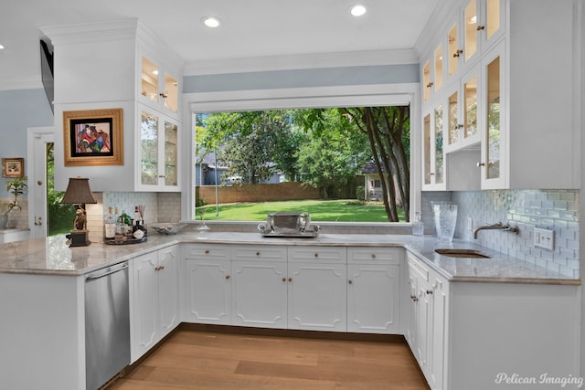 kitchen featuring light hardwood / wood-style floors, kitchen peninsula, tasteful backsplash, sink, and white cabinetry