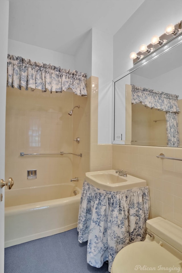 full bathroom featuring tiled shower / bath, sink, toilet, and tile walls