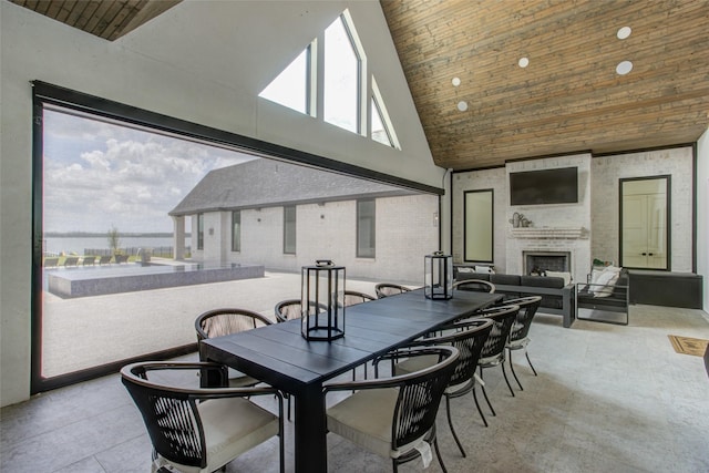 dining area featuring an outdoor brick fireplace, high vaulted ceiling, and wood ceiling