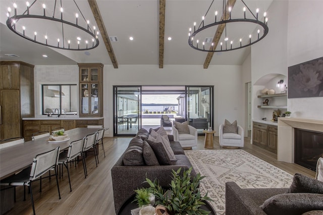 living room featuring beam ceiling, sink, high vaulted ceiling, and light hardwood / wood-style floors