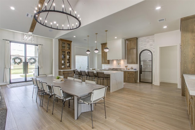 dining space with lofted ceiling, light wood-type flooring, and a notable chandelier