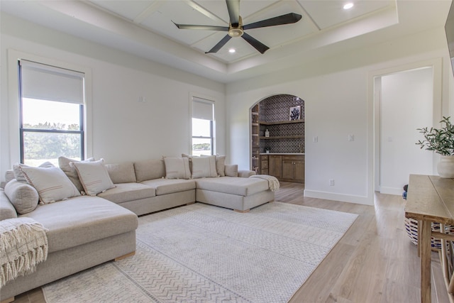 living room featuring a tray ceiling, ceiling fan, and light hardwood / wood-style floors