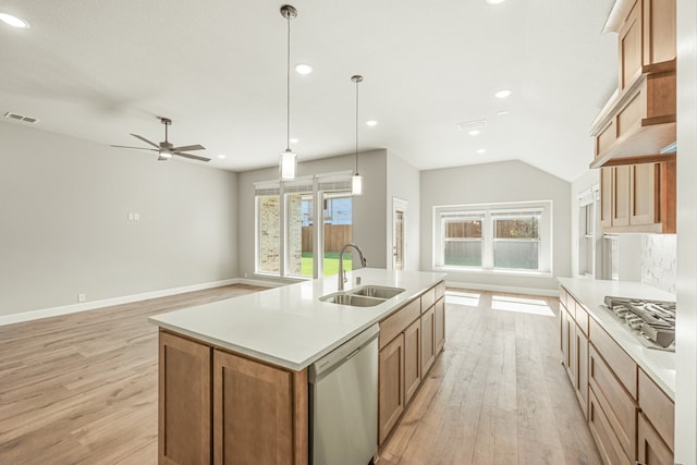 kitchen with a center island with sink, light wood-type flooring, stainless steel appliances, pendant lighting, and sink