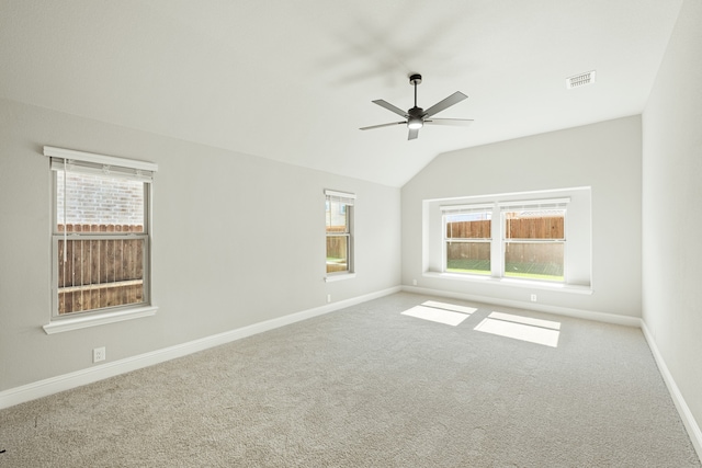 empty room with lofted ceiling, light carpet, and a healthy amount of sunlight