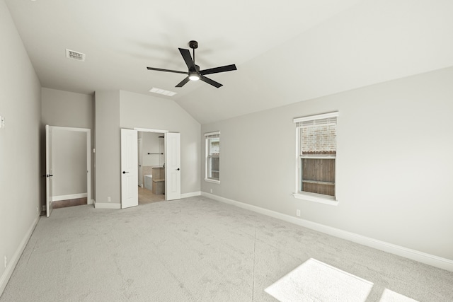 unfurnished bedroom featuring connected bathroom, ceiling fan, vaulted ceiling, and light colored carpet