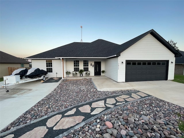 ranch-style home featuring a shingled roof, concrete driveway, and an attached garage