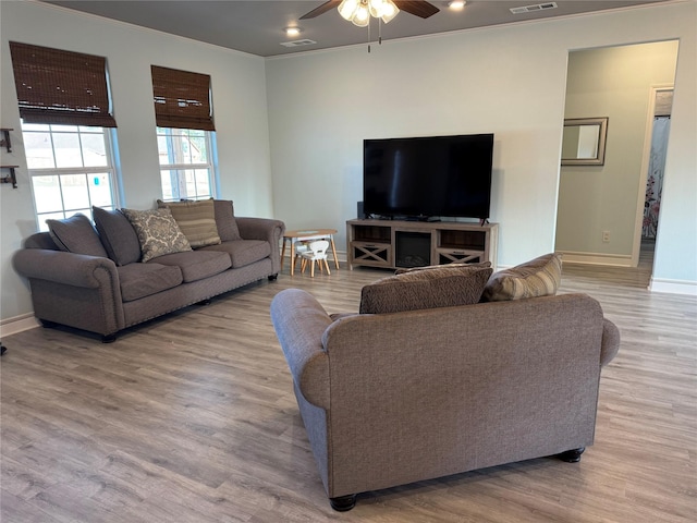 living room featuring ceiling fan, light wood-type flooring, and ornamental molding