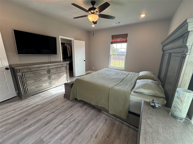 bedroom featuring ceiling fan, a closet, a spacious closet, and light wood-type flooring