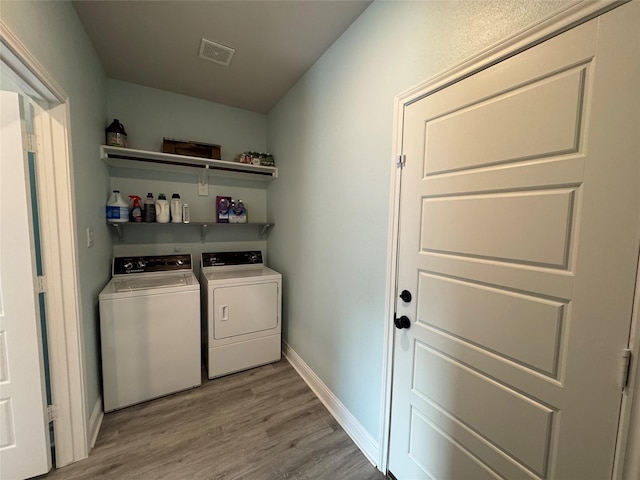 washroom with separate washer and dryer and light hardwood / wood-style flooring