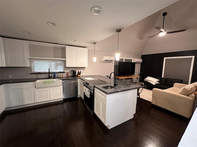 kitchen with white cabinets, open floor plan, decorative light fixtures, stainless steel appliances, and a sink