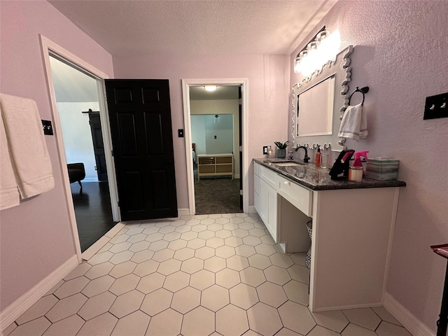 bathroom featuring baseboards, a textured ceiling, and vanity