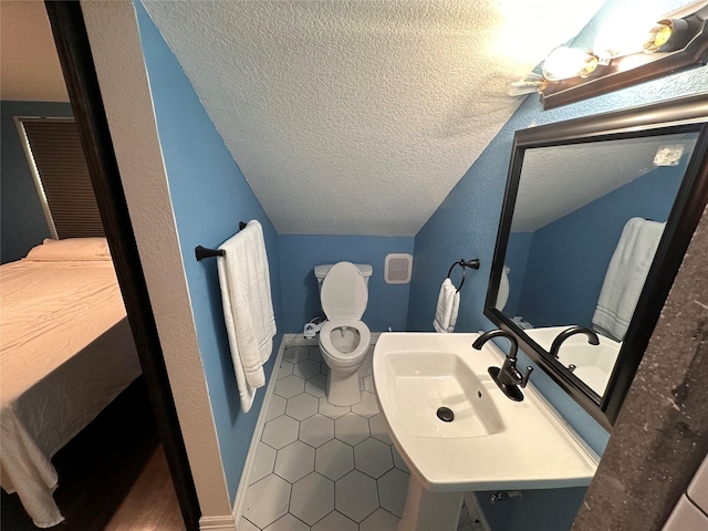 half bath featuring lofted ceiling, tile patterned flooring, a sink, and a textured ceiling