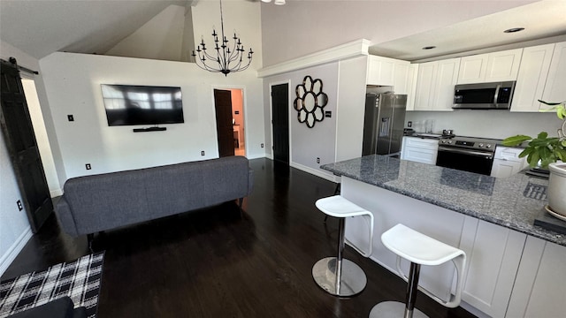 kitchen with appliances with stainless steel finishes, a barn door, a breakfast bar area, and white cabinetry