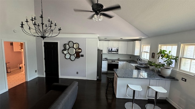 kitchen featuring a kitchen breakfast bar, a peninsula, stainless steel appliances, white cabinetry, and pendant lighting