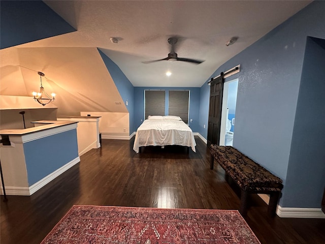 bedroom with a barn door, dark wood-type flooring, and baseboards