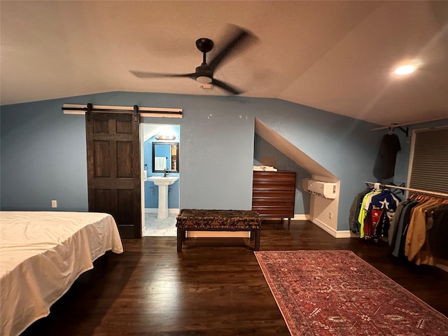 bedroom featuring lofted ceiling, a barn door, dark wood-type flooring, and baseboards