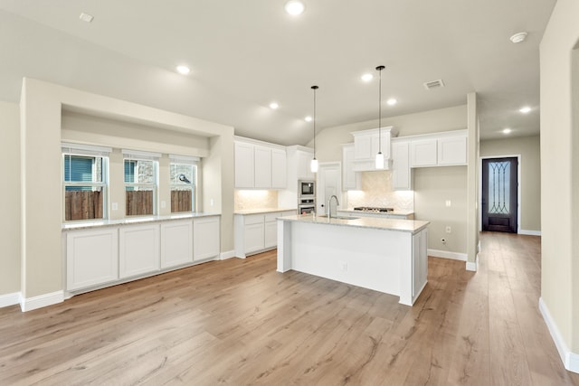 kitchen with a center island with sink, sink, white cabinetry, and light hardwood / wood-style flooring