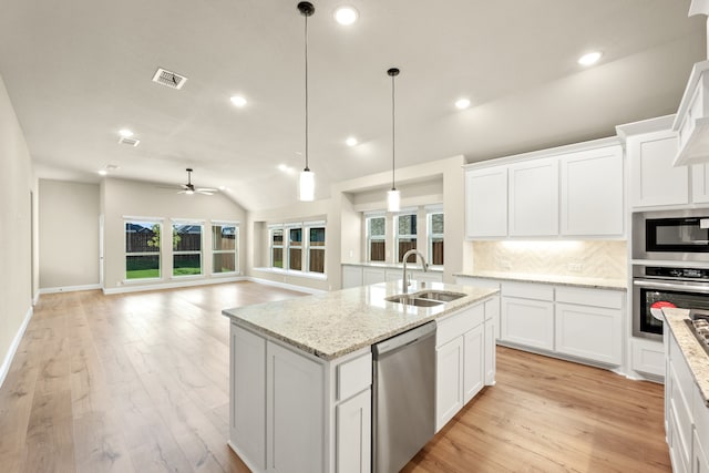 kitchen with vaulted ceiling, appliances with stainless steel finishes, sink, and white cabinets