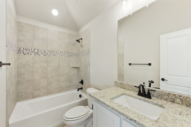 full bathroom featuring toilet, tiled shower / bath, vanity, and vaulted ceiling